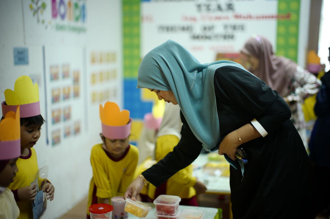 Teacher guiding young pupils in a classroom